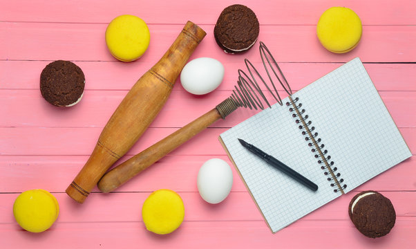 The process of making chocolate cookies, macaroons, ingredients on a pink wooden background. Eggs, rolling pin, corolla, recipe notebook with a pen. Top view. - Powered by Adobe
