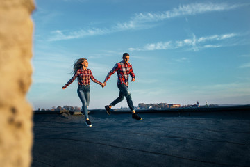 The lovely couple in love running along roof