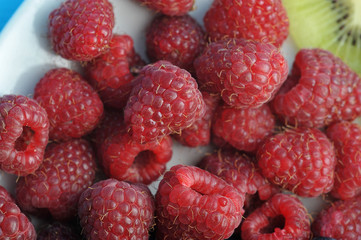 Berries of ripe raspberries on a white plate. View from above. Close-up. Macro photography.