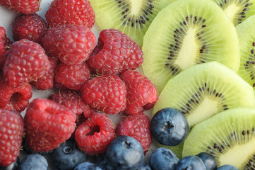 Background of ripe raspberries, blueberries and kiwi slices. View over. Close-up. Macro photography.