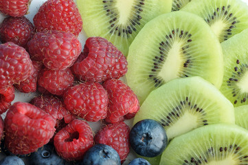 Background of ripe raspberries, blueberries and kiwi slices. View over. Close-up. Macro photography.