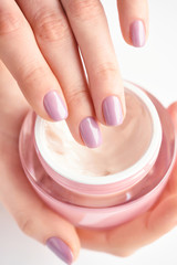 Hands of a woman with pink manicure with cream