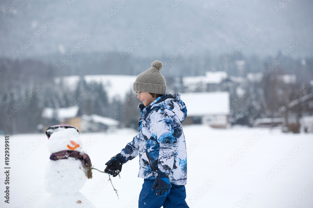 Canvas Prints Family with children, building snowman in the park in little village in Austria