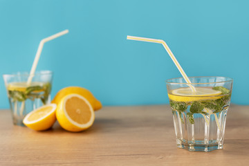 close-up glass transparent glass with water lemon and a straw on a wooden table and on a blue...