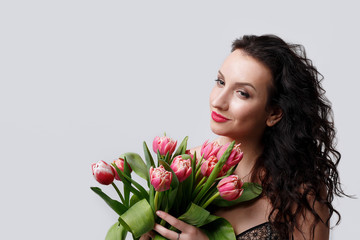 portrait of a girl with red lips which holds a bouquet of pink tulips on a white background with a wire for text