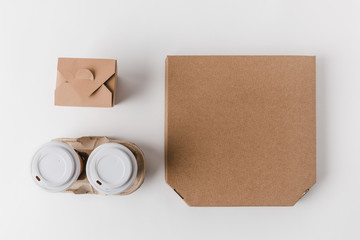 top view of pizza box and disposable coffee cups with noodles box on white