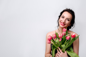 portrait of a girl with red lips and big smile which holds a bouquet of pink tulips on a white background with a wire for text
