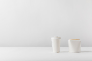 disposable coffee cup and noodles box on white surface