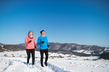 Senior couple jogging in winter nature.