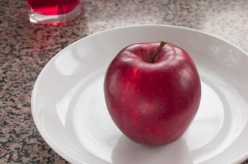Burgundy apple on a white plate