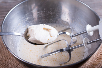 Cooking, whipping eggs with electric whisk in bowl with sour cream