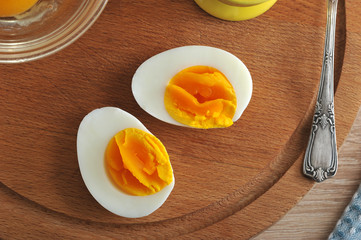 Hard-boiled eggs. Two halves  on a wooden tray. View from above. Closeup.