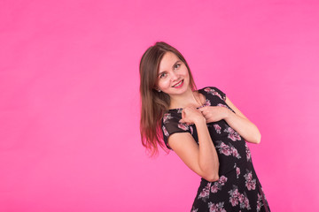 Young woman in a dress on a pink background