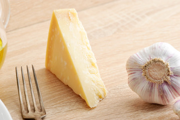 Parmesan cheese and garlic head. Wooden beige background. Close-up.