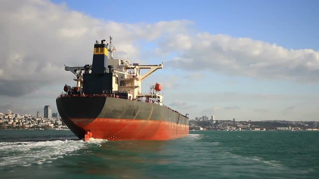 Stern and funnel of an empty tanker ship sailing into the sea under blue sky. Back view of a 290 meters long crude oil tanker ship on route to Black Sea. Bosporus Straits in Istanbul, Turkey