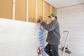 Construction worker thermally insulating eco wooden frame house with wood fiber plates. Latvia