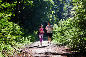 A man and a sportive woman Jogging in the woods in the morning.