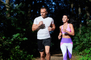 A man and a woman sporting on a Sunny day, do exercises in the forest.