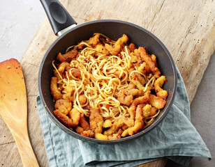 Asian noodles with fried meat on cooking pan