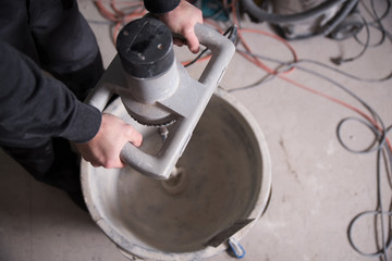 Handwerker arbeitet auf einer Baustelle mit einem Rührgerät 