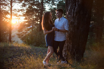 Loving couple at sunset. Near a tree. Holding hands.