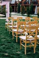 Open air wedding ceremony, wooden chairs in row on the grass