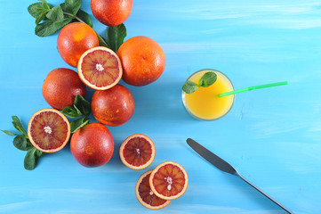 Red Sicilian oranges. Several oranges are cut in half and into slices. Next to a glass of orange...