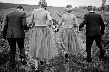 Groomsmen and bridesmaids running in blackcurrant field on a wedding day. Black and white photo.