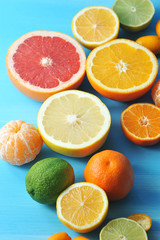 Assorted citrus fruits. In the frame, lime, kumquat, mandarin without peel, halves of orange, mandarin, lemon, grapefruit, lime. Blue wood background. Close-up. Vertical orientation of the frame.