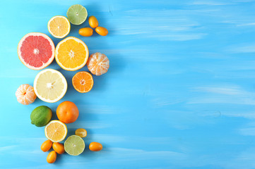 Collage of citrus. In the frame, lime, kumquat, mandarin without peel, halves of orange, mandarin, lemon, grapefruit, lime. Blue wood background. Close-up. View from above.