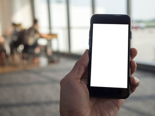 Closeup  image of hand holding black mobile phone with blank white screen in  airport terminal background