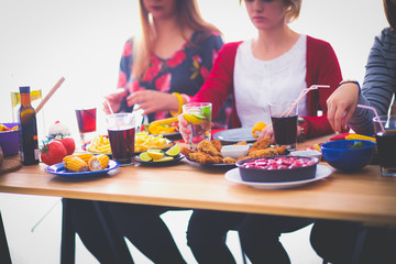 Top view of group of people having dinner together while sitting at wooden table. Food on the table. People eat fast food.
