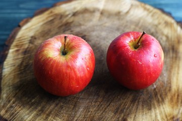 Two sweet ripe juicy red apples on chopped wood close up