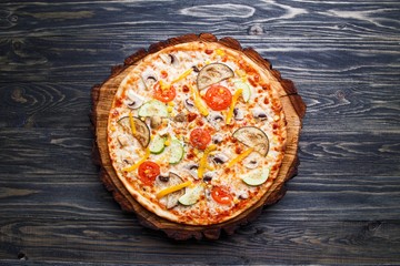 Appetizing vegetarian pizza with tomato, zucchini, eggplant, olives and mushrooms, top view. Delicious Italian food, restaurant menu photo