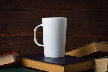 White Cup With Hot Coffee on Deployed Books on a Dark Wooden Background