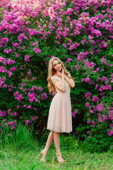 Beautiful woman enjoying lilac garden, young woman with flowers in green Park, blonde girl, spring nature photo shoot