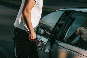 Young attractive caucasian man in white t-shirt standing by the car