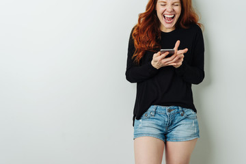Young woman laughing loudly at a text message
