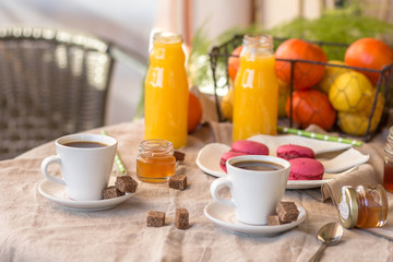 Breakfast with coffee cups, orange juice, makaron the outdoor terrace