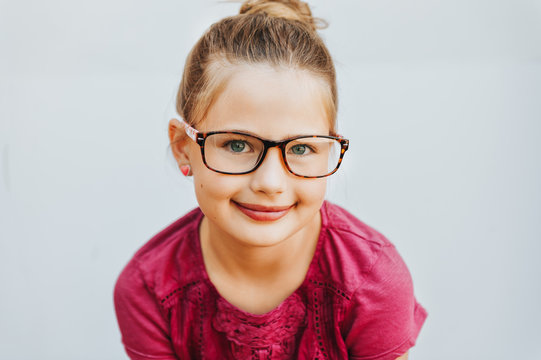 Outdoor portrait of adorable kid girl wearing glasses