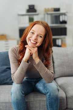 Young cheerful woman sitting on sofa at home