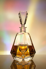 Crystal decanter with a drink and a wineglass on a colorful background