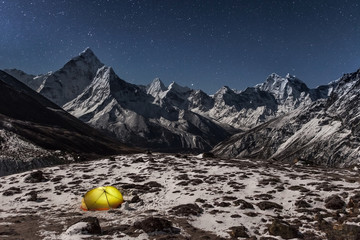 Concept of solitude and freedom in the wild. Night winter camping in the mountains. Lonely tent lit...