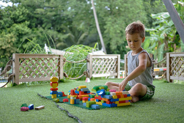 Boy playing with plastic construction toys. Amusement playground. Thailand