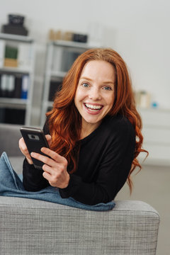 Young smiling woman with mobile phone on sofa