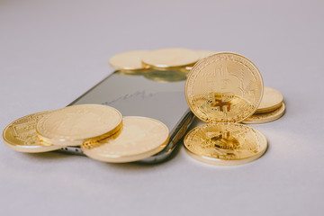 Bitcoin (BTC). Crypto currency. Macro shot of golden coins placed on smartphone. Blockchain technology, bitcoin mining concept.
