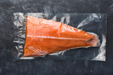 Salmon fillet packaged in plastic vacuum pack. Fresh fish in packing sell in supermarket. Metal...