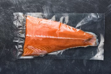 Fotobehang Salmon fillet packaged in plastic vacuum pack. Fresh fish in packing sell in supermarket. Metal black background © romanovad