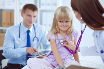 Female doctor examining child with stethoscope at surgery