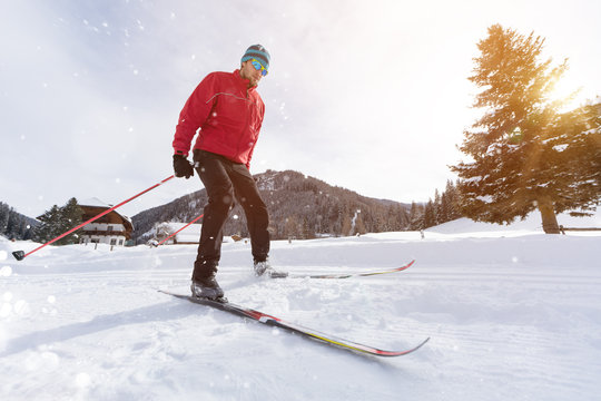 Man cross-country skiing during sunny winter day.